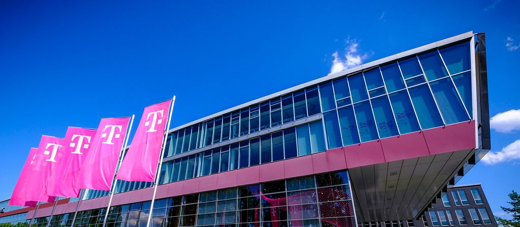 A Telekom building photographed from below with Telekom flags in front of it