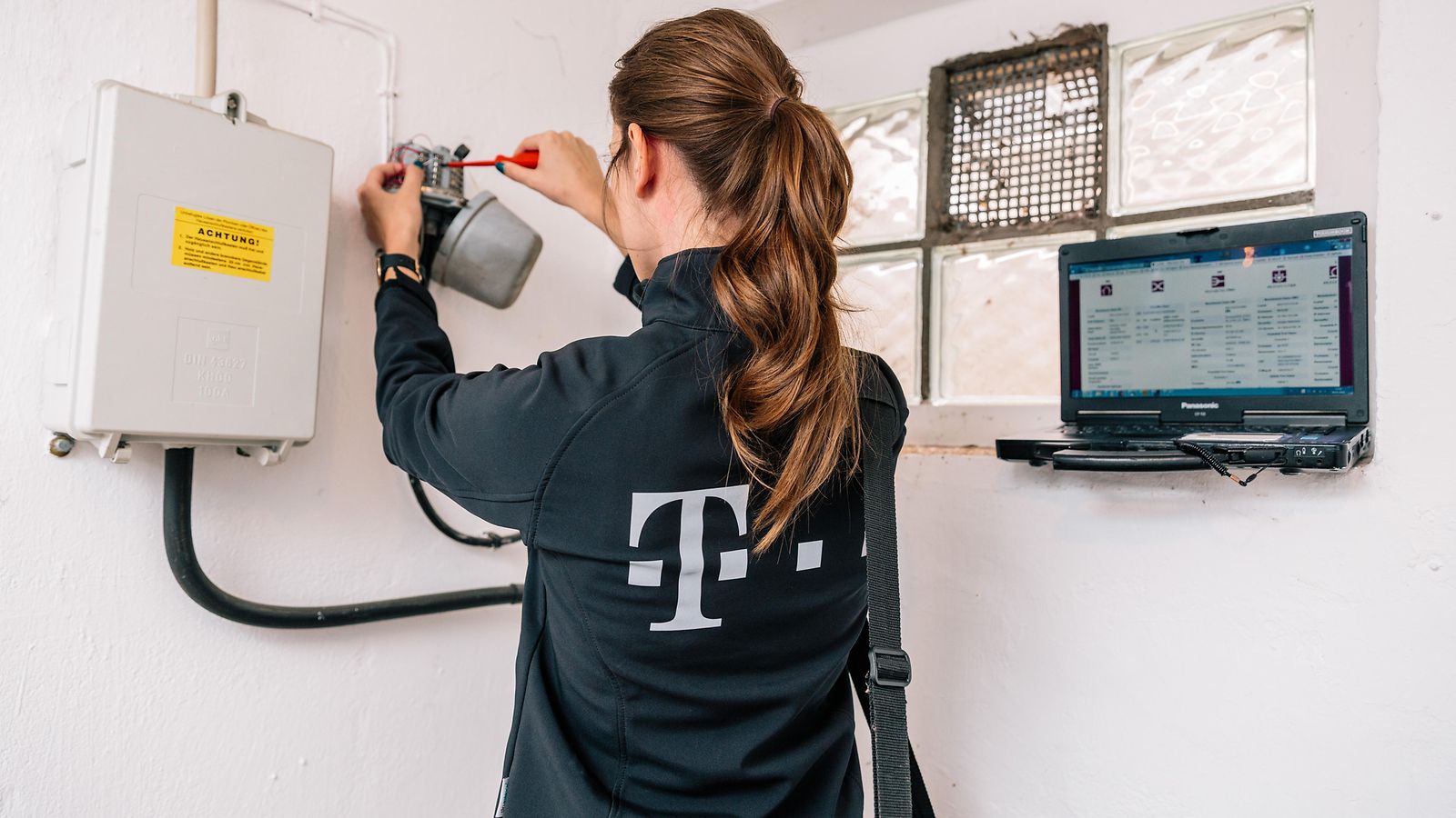 A Telekom service technician is working on a cable box