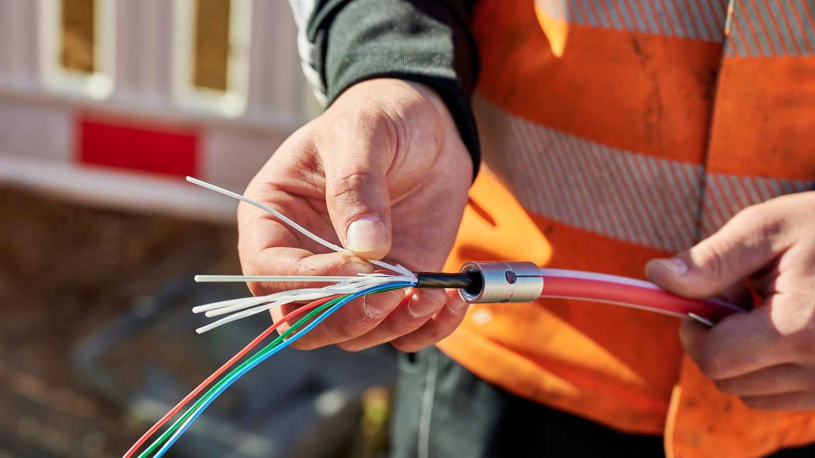 A construction worker with a fiber optic cable in his hand